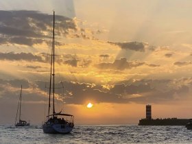 Sailboats glide through the water at sunset, creating a picturesque scene in the harbor — perfect for romantic evenings or scenic cruises.