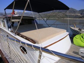 A cozy lounge area on a boat featuring a comfortable seating cushion, perfect for relaxing while enjoying the scenic views.
