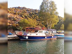 A beautiful yacht docked at a serene harbor, surrounded by lush greenery and rocky hills, perfect for exploring coastal destinations.