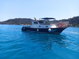 A beautiful view of the Ayla boat cruising through crystal-clear waters, surrounded by lush greenery — perfect for exploring coastal destinations.