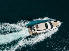 Aerial view of a sleek yacht cruising through deep blue waters, showcasing its elegant design and smooth wake.