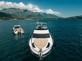 A stunning aerial view of two boats cruising in clear waters, showcasing the beauty of yachting against a backdrop of mountains — perfect for exploring coastal destinations.