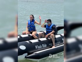 Two friends enjoy a thrilling whale ride in the water, showcasing fun and excitement during their aquatic adventure.