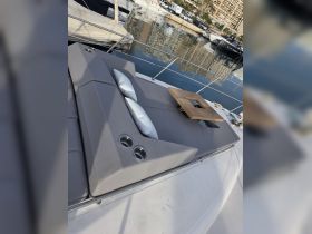A cozy lounge area on a yacht featuring comfortable seating and cup holders, perfect for relaxing while enjoying the marina views.