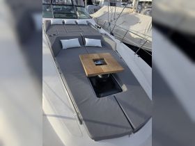 A cozy lounge area on the deck of a yacht, featuring comfortable cushions and a wooden table, perfect for relaxation and socializing while enjoying the open water.