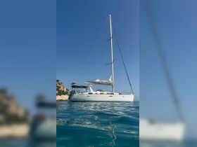 A stunning sailboat glides through clear waters, showcasing its elegant design against a backdrop of blue skies — perfect for sailing enthusiasts and charters.
