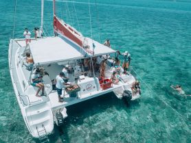 A lively group enjoys a day on a catamaran, with activities including swimming and a barbecue, showcasing the perfect blend of fun and relaxation on the water.