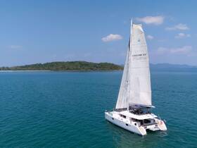 A stunning aerial view of a catamaran sailing in clear turquoise waters, showcasing the beauty of Chalong Bay and its serene surroundings.