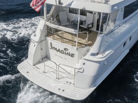 A stunning view of the back of the yacht 'Imagine' cruising through the waves, showcasing its sleek design and spacious deck — perfect for luxury outings on the water.