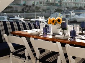 Elegant dining setup inside a boat, featuring a beautifully arranged table with sunflowers and stylish glassware, perfect for intimate gatherings or special occasions on the water.
