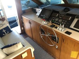 A well-equipped helm area inside a yacht, featuring modern navigation controls and a comfortable seating area, perfect for steering adventures on the water.
