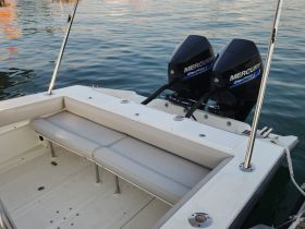 Interior view of a boat's seating area, featuring comfortable cushions and twin Mercury outboard motors, perfect for a day on the water.
