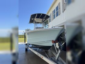 A pristine center console boat is showcased in front of a house, highlighting its sleek design and readiness for adventure.
