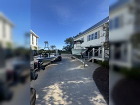 Two boats are docked in a driveway, showcasing their sleek designs against a clear blue sky — perfect for fishing or leisure outings.