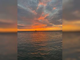 A stunning sunset casts vibrant colors over the water, creating a picturesque scene perfect for evening boat trips or romantic getaways.