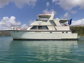 A beautiful yacht named 'Hiramar' docked in calm waters, showcasing its elegant design against a picturesque backdrop.