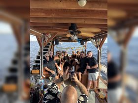 A lively group of friends celebrates together on a boat, enjoying drinks and capturing memories — perfect for parties and gatherings on the water.