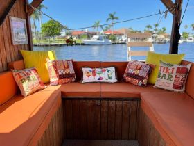 Cozy interior of a boat featuring vibrant tiki bar-themed cushions and seating, perfect for relaxing on the water.