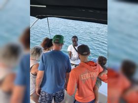 A group of guests gathers around a crew member on a boat, enjoying a culinary experience on the water — perfect for family outings and memorable trips.