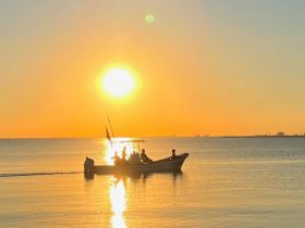A picturesque sunset view featuring a boat with people enjoying the serene waters, creating a perfect backdrop for memorable moments on the water.