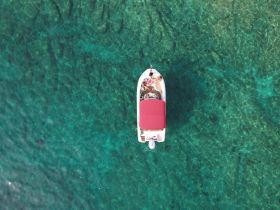 Aerial view of a boat cruising over crystal-clear waters, showcasing the vibrant underwater scenery — perfect for exploring and enjoying the beauty of the ocean.