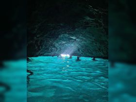 A group of swimmers enjoys the stunning turquoise waters inside a cave, illuminated by natural light — a breathtaking adventure in a unique underwater setting.