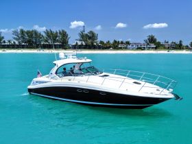 A sleek speedboat glides through turquoise waters, showcasing its elegant design against a picturesque beach backdrop — perfect for thrilling water adventures.