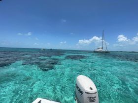 A stunning view of a catamaran anchored in crystal-clear waters, with swimmers enjoying the vibrant marine environment — a perfect scene for island adventures.