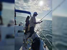 A group enjoys a fishing trip on a boat under the bright sun, capturing the essence of a fun day on the water.