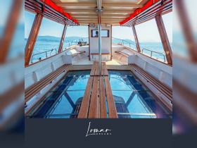 Interior view of a boat cabin featuring wooden seating and a glass floor, providing a unique perspective of the water below — perfect for relaxing while cruising.