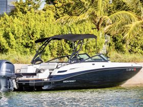 A sleek Monterey speedboat named 'Rocky IV' docked by the shore, showcasing its stylish design against a lush green backdrop.