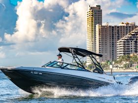 A speedboat glides through the water with a captain at the helm, showcasing a vibrant city skyline in the background — perfect for thrilling water adventures.