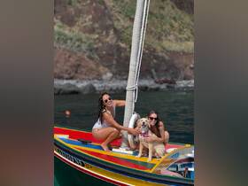 Two women enjoy a sunny day on a colorful boat with their dog, capturing a joyful moment on the water — perfect for pet-friendly adventures.