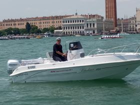A boat operator navigates through the vibrant waters of Venice, showcasing the unique architecture and lively atmosphere of this iconic city.