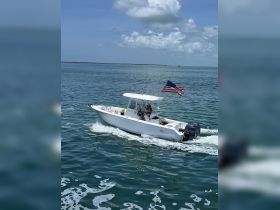 A speedboat navigates through clear waters, showcasing a scenic day on the ocean with a passenger at the helm.