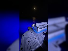 A serene nighttime view of the interior seating area of a boat, illuminated by blue lights, creating a tranquil atmosphere perfect for evening cruises.