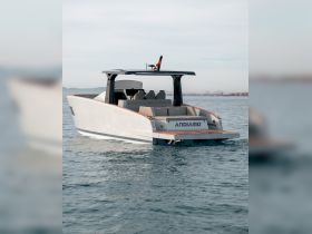 A sleek view of the Andiamo yacht cruising through calm waters, showcasing its modern design and spacious seating.