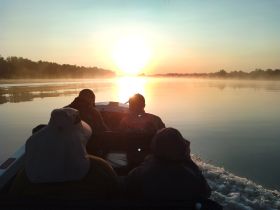 A group enjoys a serene sunrise on the water, capturing the tranquil beauty of early morning boating adventures.