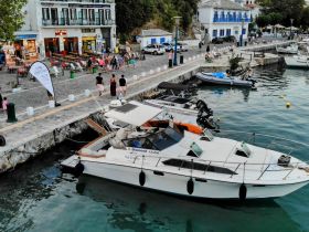 A view of a boat docked at a marina, surrounded by people enjoying the waterfront atmosphere — perfect for exploring local shops and dining.