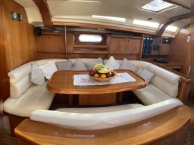 Cozy interior of a boat featuring a comfortable seating area and a dining table adorned with a bowl of fresh fruit, perfect for relaxing and enjoying meals on the water.