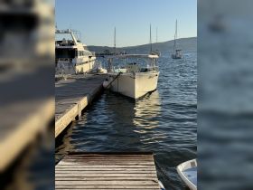 A serene view of a boat docked at a marina, surrounded by calm waters and other vessels in the background, perfect for showcasing boating adventures.