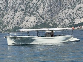 A sleek speedboat named 'Fracraft' glides through clear waters, surrounded by stunning mountainous scenery — perfect for exploring coastal destinations.