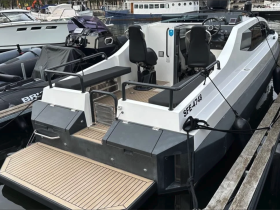 A sleek speedboat docked at the marina, showcasing its modern design and spacious rear deck, perfect for day trips on the water.