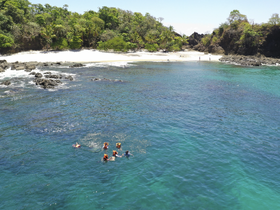A group enjoys a refreshing swim in crystal-clear waters near a secluded beach, perfect for snorkeling and beach adventures.