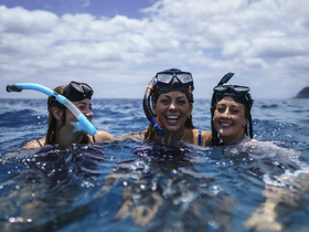A joyful group of friends enjoys snorkeling in the ocean, capturing the essence of adventure and fun in the water.