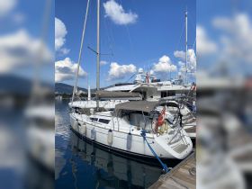 A beautiful Sun Odyssey yacht docked at the marina, showcasing its sleek design against a backdrop of clear blue skies and calm waters.