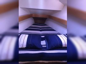 Cozy cabin interior featuring a neatly made bed with blue and white striped bedding, perfect for relaxing on a boat.