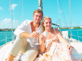 A couple enjoys cocktails on the deck of a yacht, capturing a perfect moment of celebration under the sun — ideal for romantic getaways or special occasions.