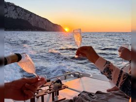 A couple toasts with sparkling drinks as the sun sets over the horizon, creating a romantic atmosphere perfect for sunset cruises on a yacht.