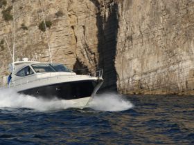 A sleek speedboat cuts through the waves, showcasing its dynamic design against a stunning rocky backdrop — perfect for thrilling water adventures.